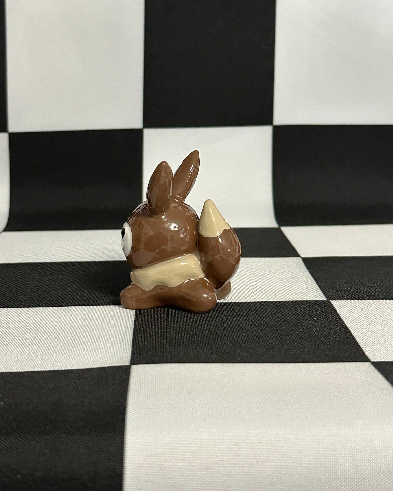Small brown figurine on a black and white checkered background