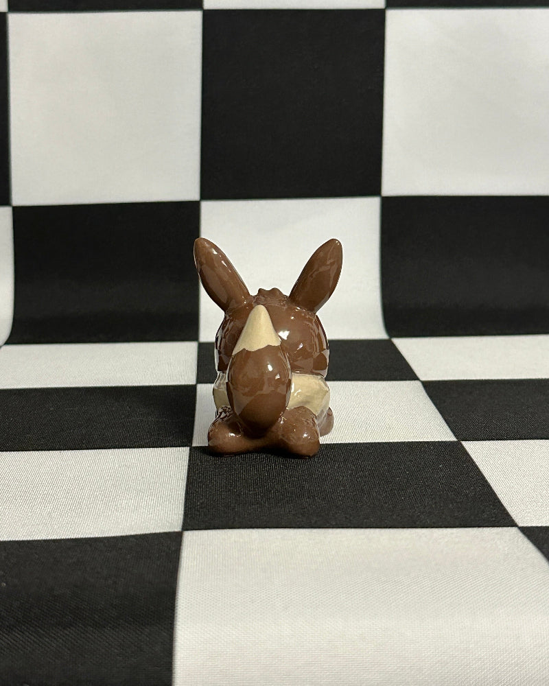 Small figurine of a creature on a black and white checkered background