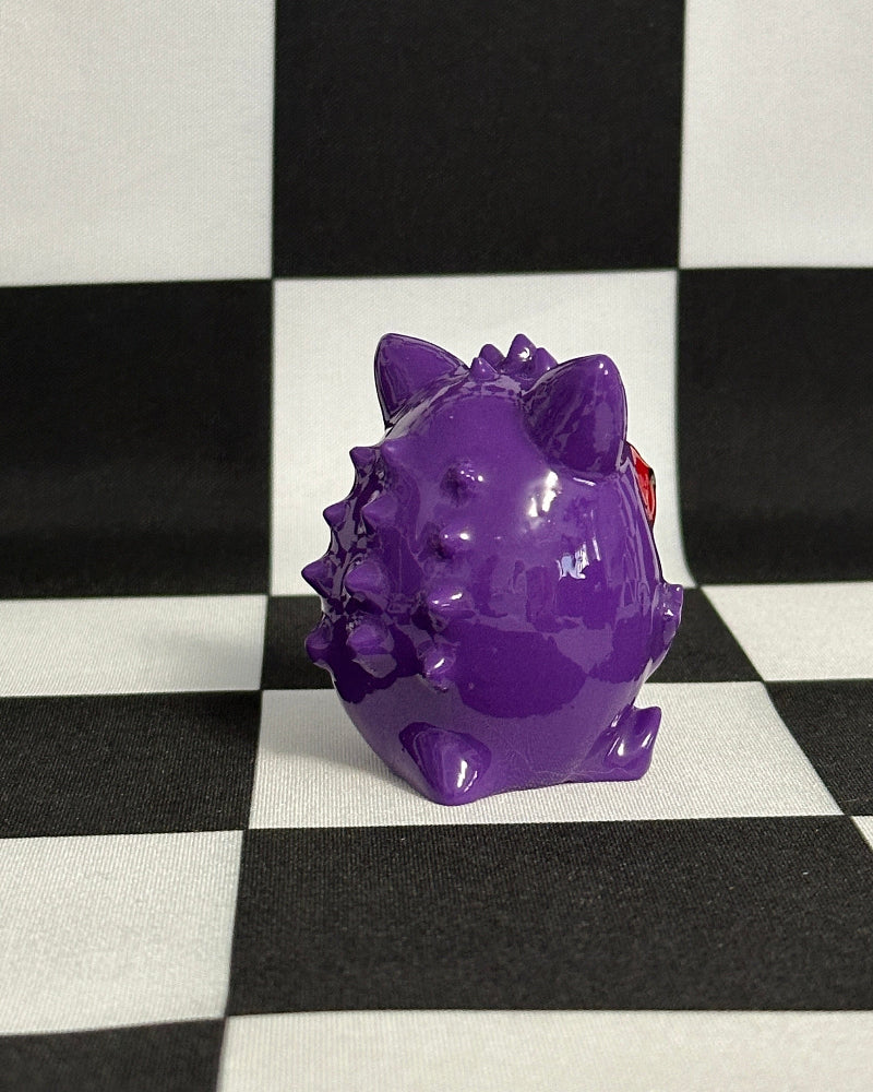 Purple dinosaur figurine on a black and white checkered background