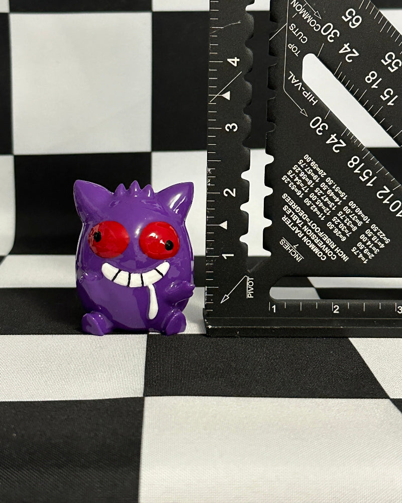 Purple cartoon-like creature with red eyes and a ruler on a checkered background