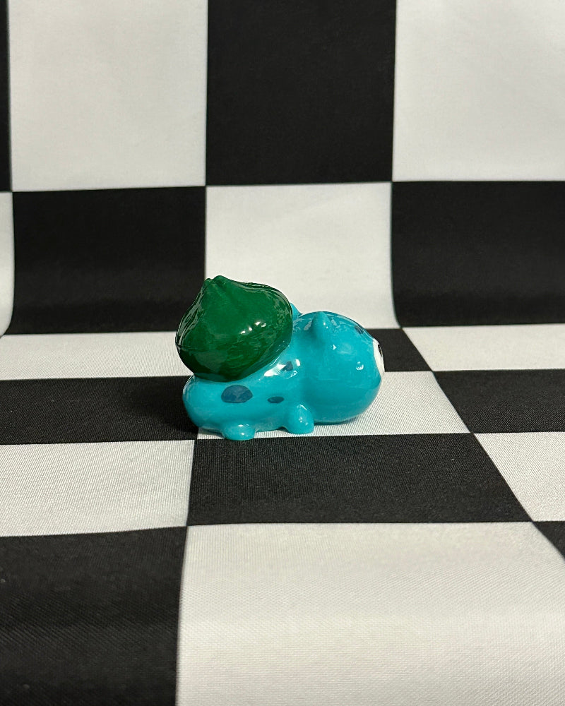 Small blue and green figurine on a black and white checkered background