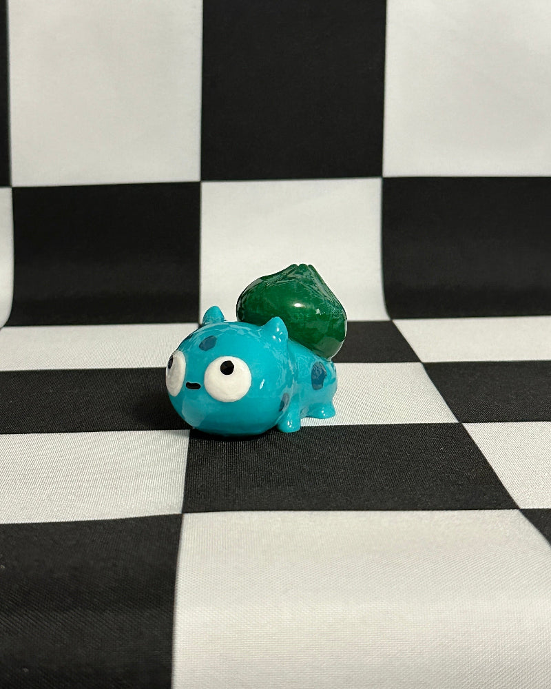 Blue and green monster figurine on a black and white checkered background