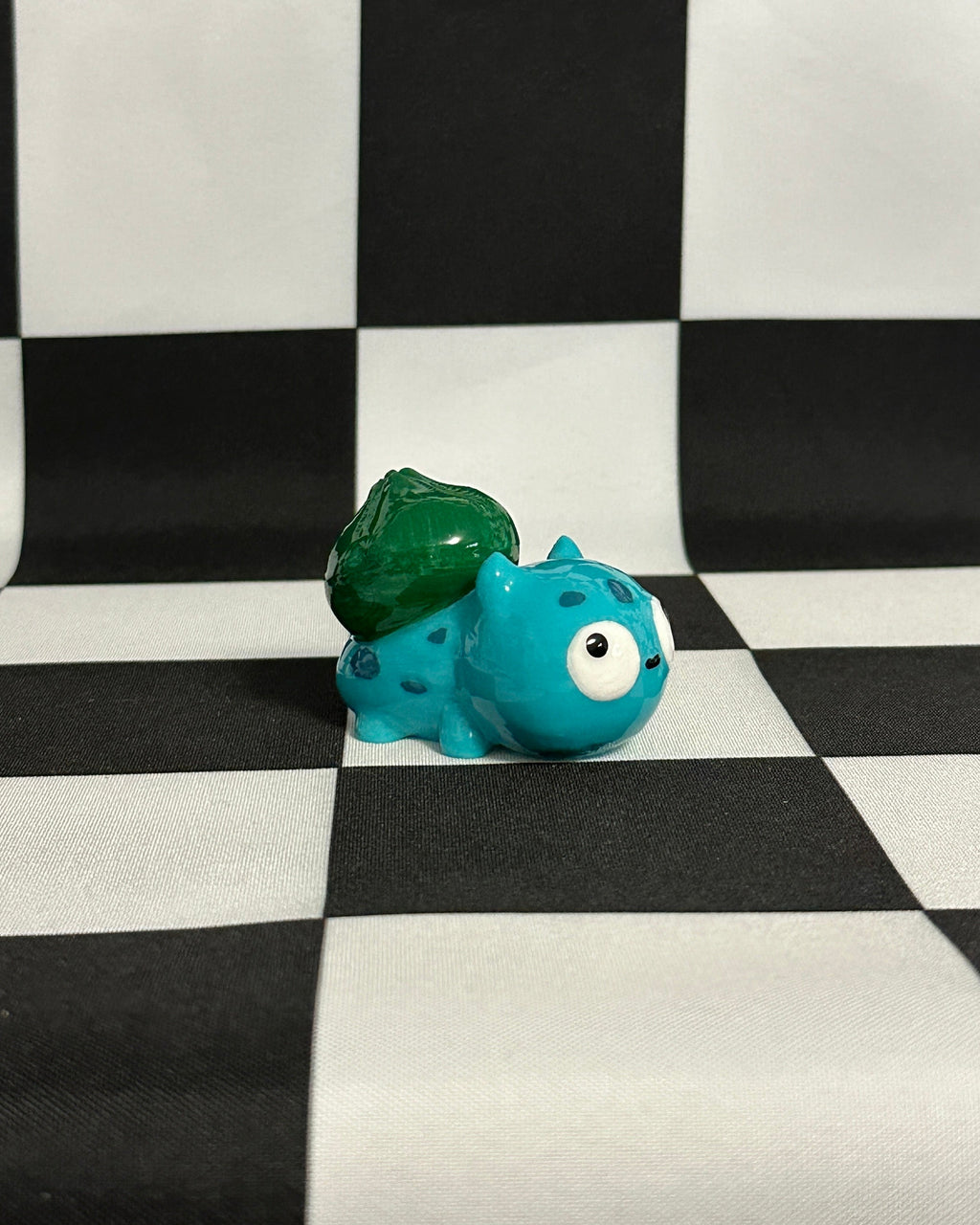 Blue and green toy figure on a black and white checkered background