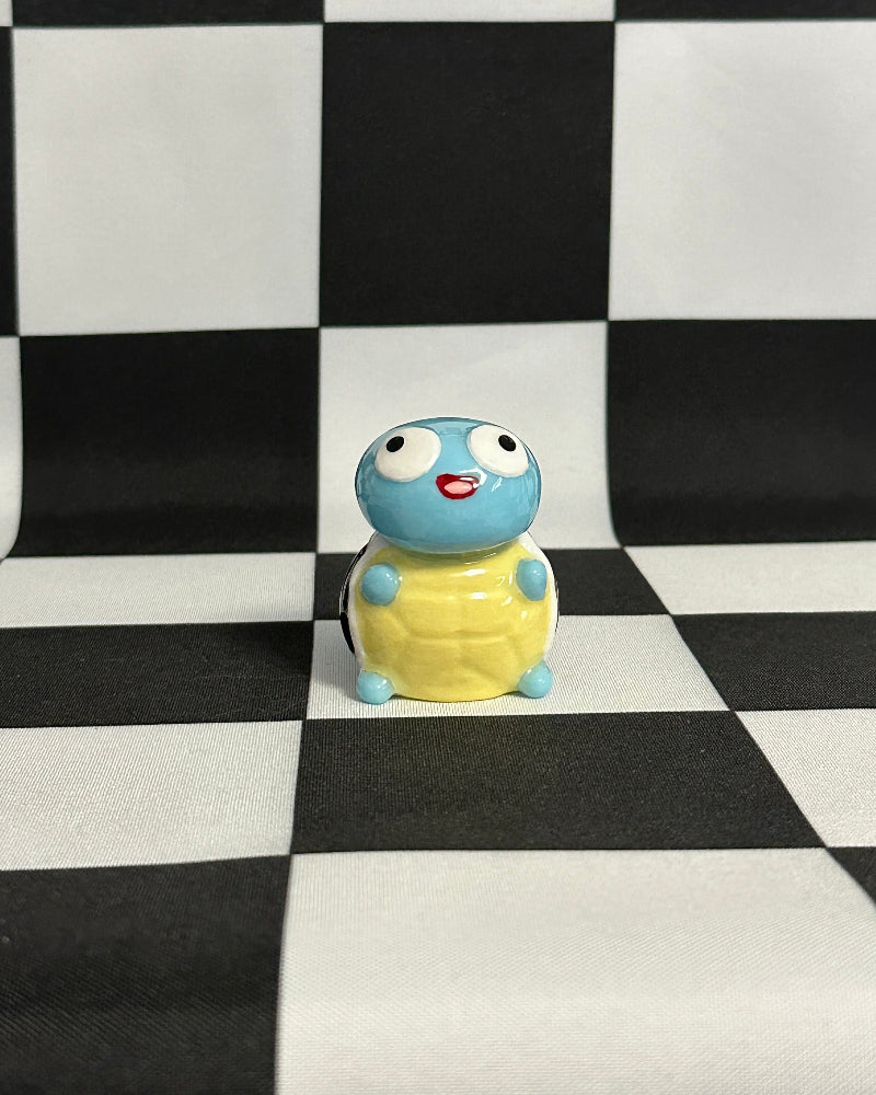 Small blue and yellow figurine on a black and white checkered background
