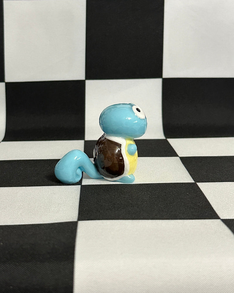 Small blue figurine with a brown shell on a black and white checkered background