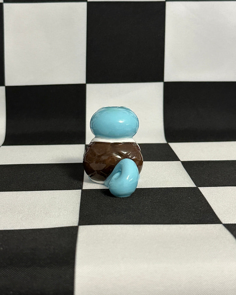 Two small glass bottles with blue and brown colors on a black and white checkered background