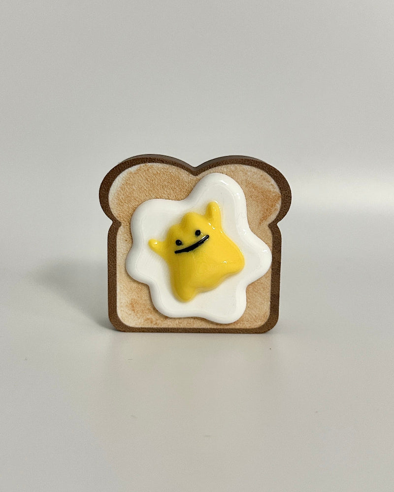 Pin with a design of a smiley face egg on toast against a light gray background