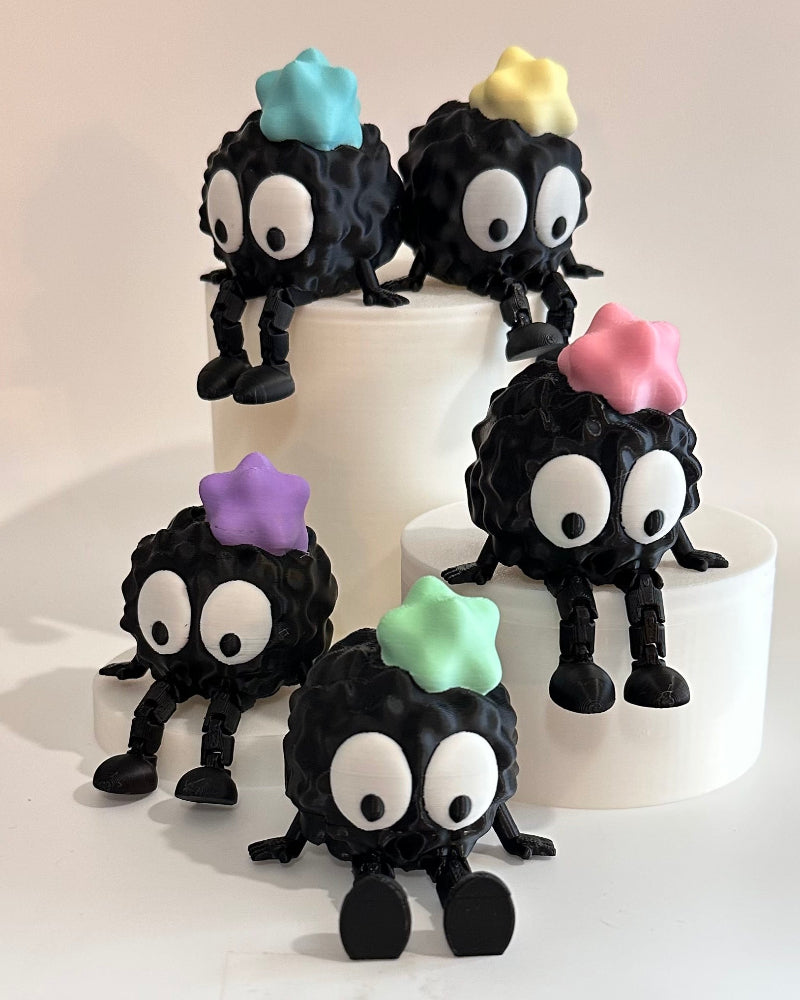 black characters on a stand, resembling small creatures with colorful stars.
