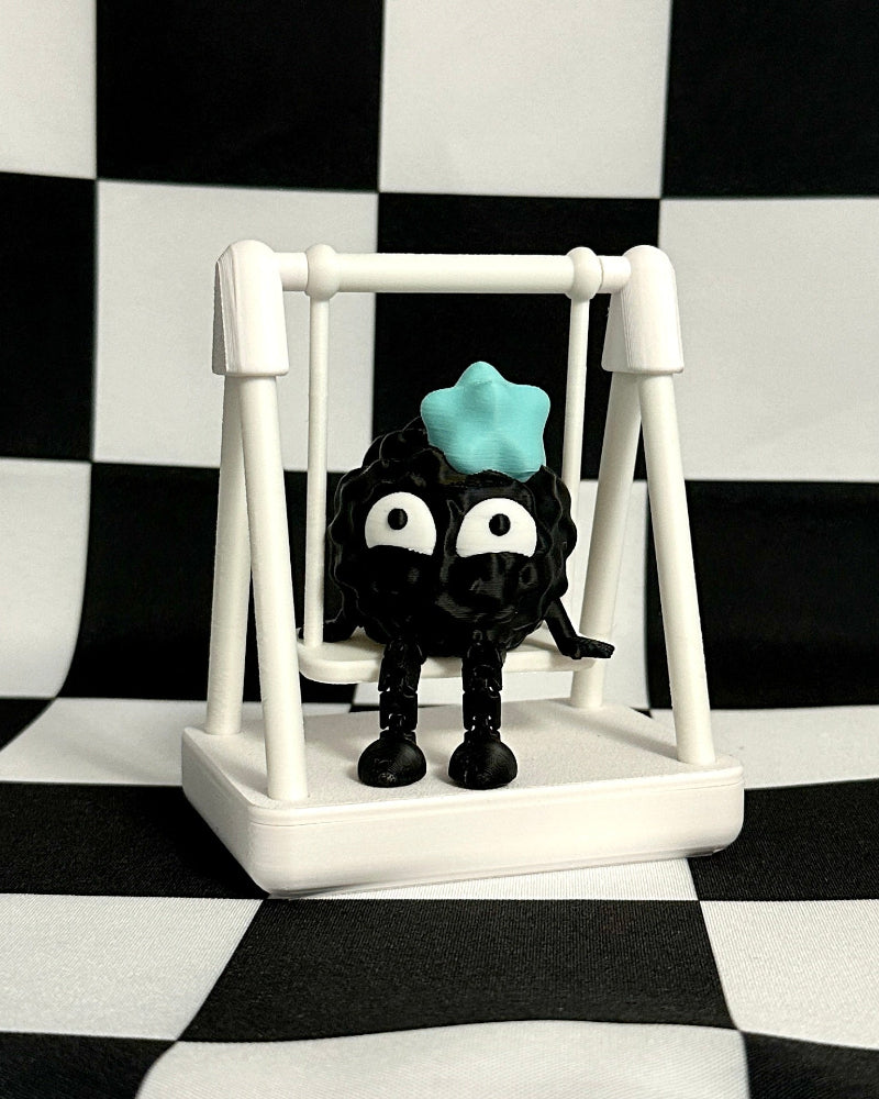 Black cat toy with a blue ball on a white swing against a black and white checkered background