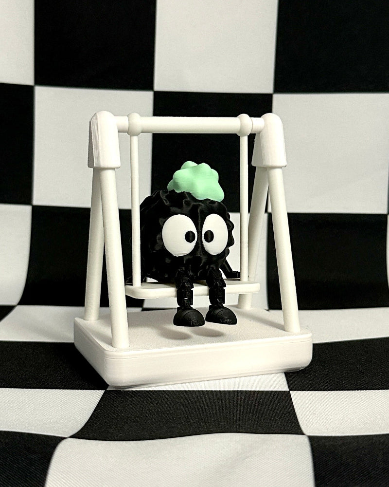 Small black and white figure with a green head on a swing against a black and white checkered background