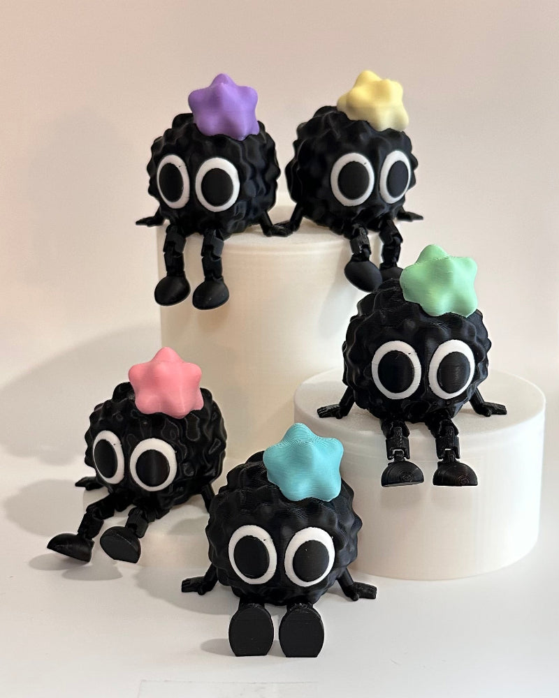 Small black figures with colorful hair on a white cake
