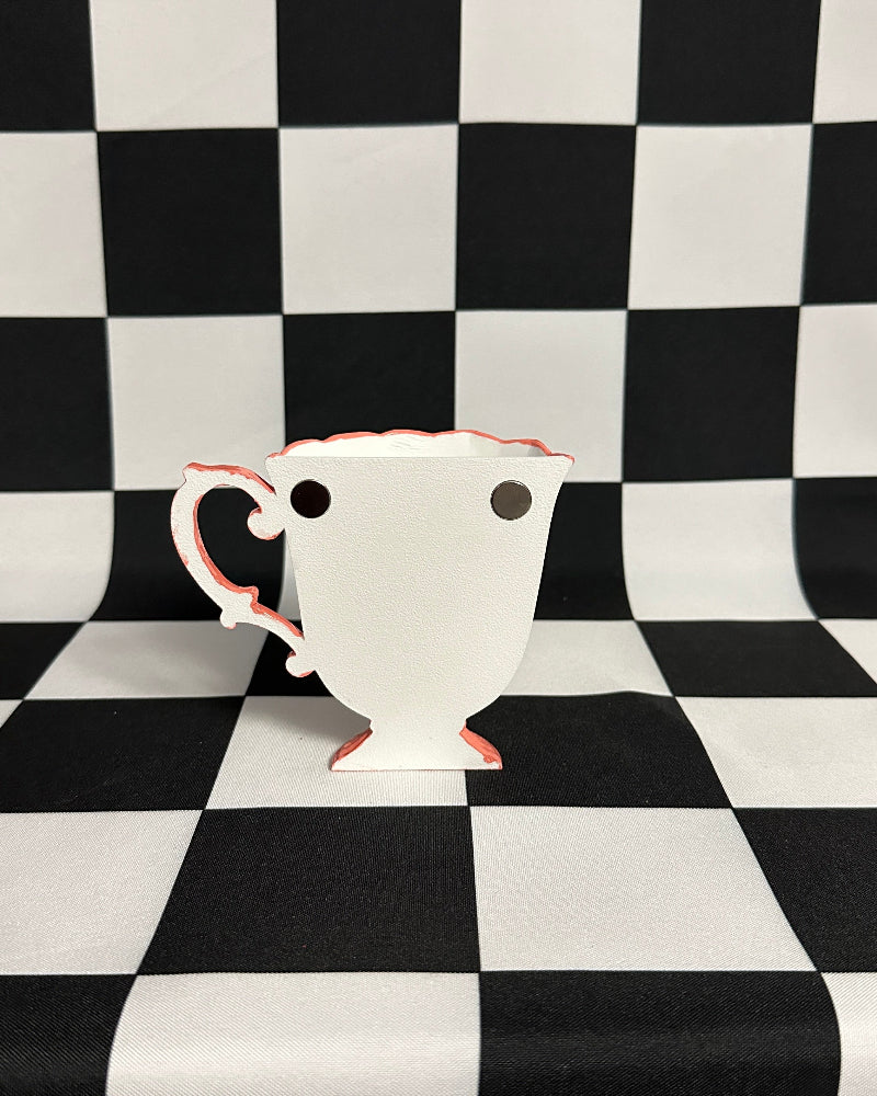 White teacup with pink handle on a black and white checkered background