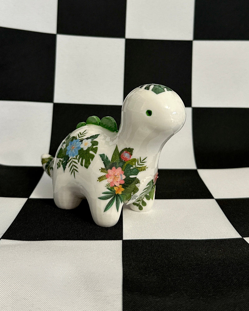 Decorative ceramic dinosaur with floral patterns on a black and white checkered background