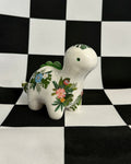 Decorative ceramic dinosaur with floral patterns on a black and white checkered background