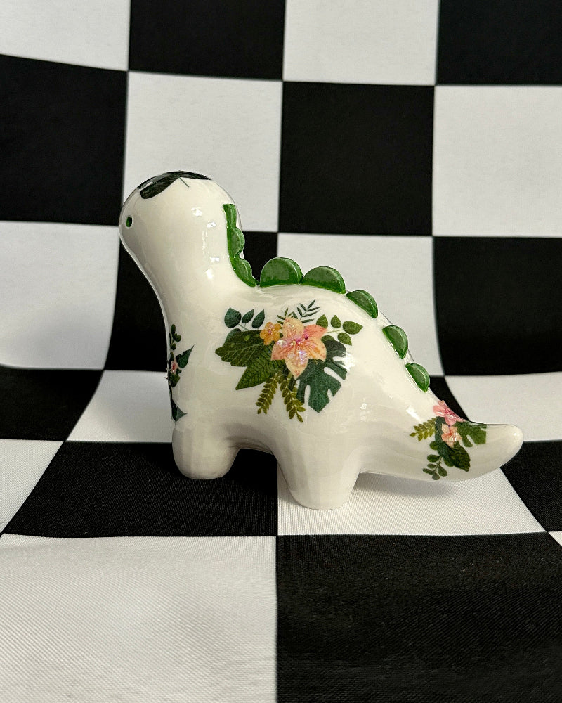 Ceramic dinosaur figurine with floral patterns on a black and white checkered background