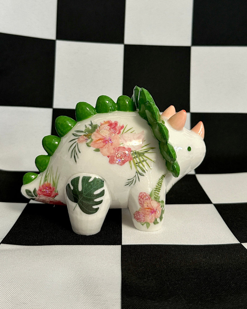 Decorative ceramic dinosaur with floral patterns on a black and white checkered background