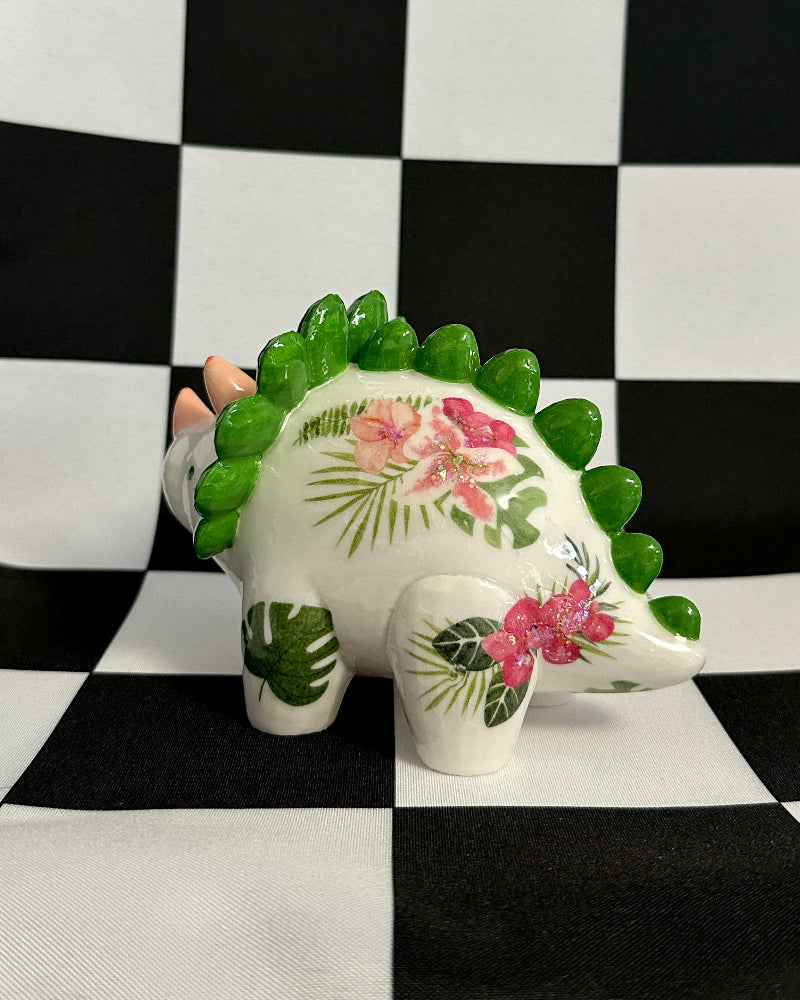 Decorative dinosaur figurine with floral design on a black and white checkered background
