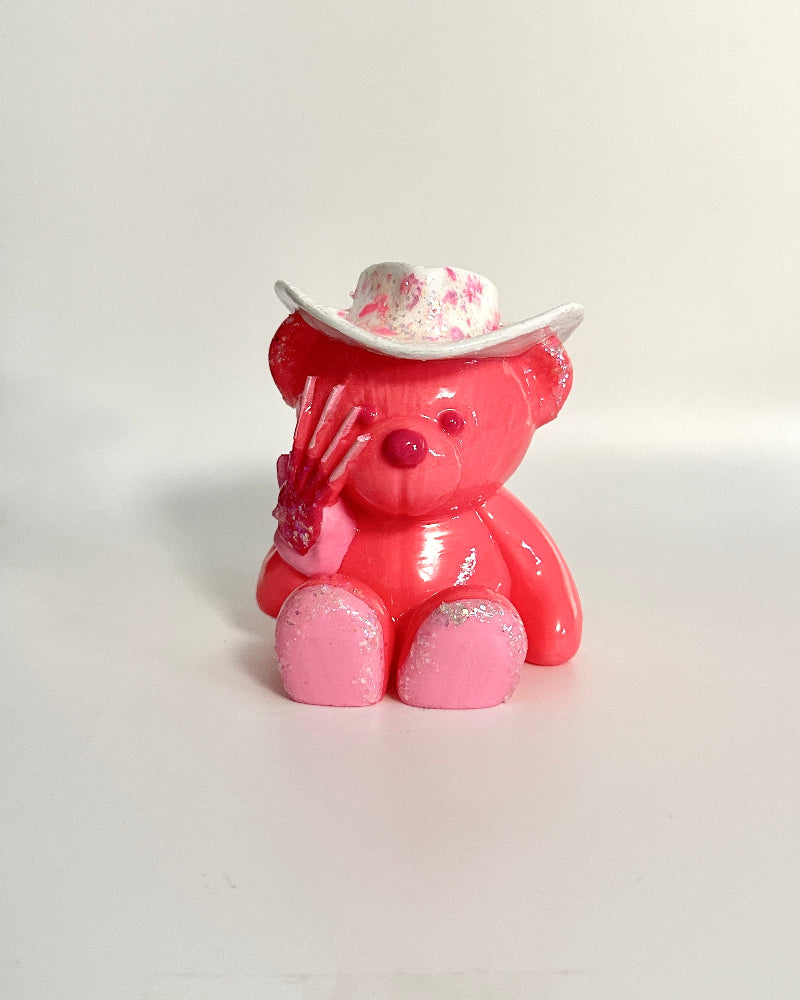 Pink teddy bear figurine with a white hat on a white background