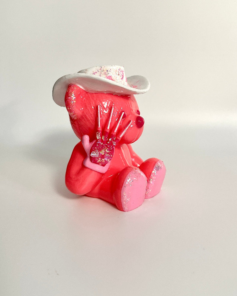 Pink teddy bear figurine with a white hat on a white background