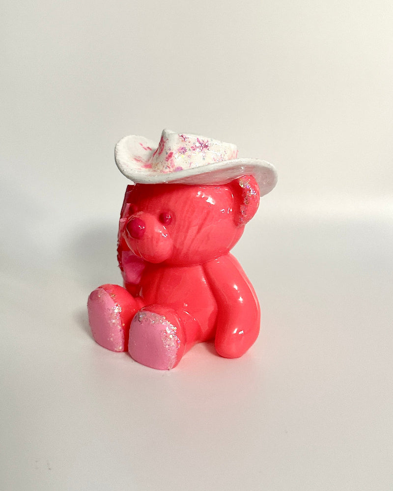 Pink teddy bear figurine wearing a white hat on a white background