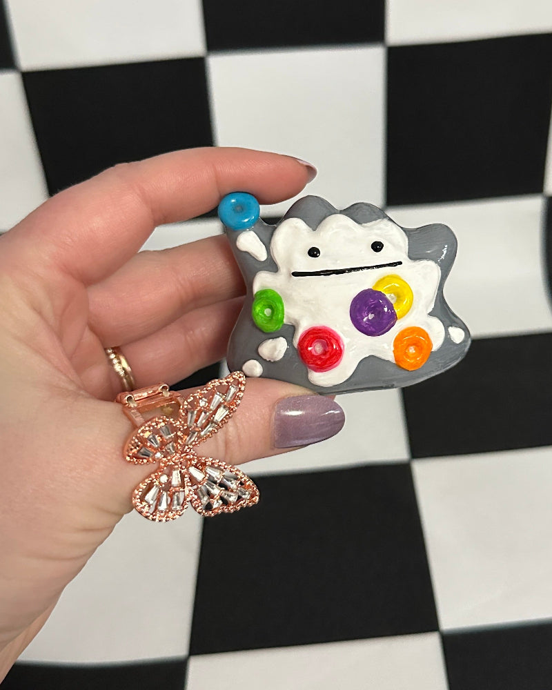 Hand holding a colorful character sticker on a checkered background