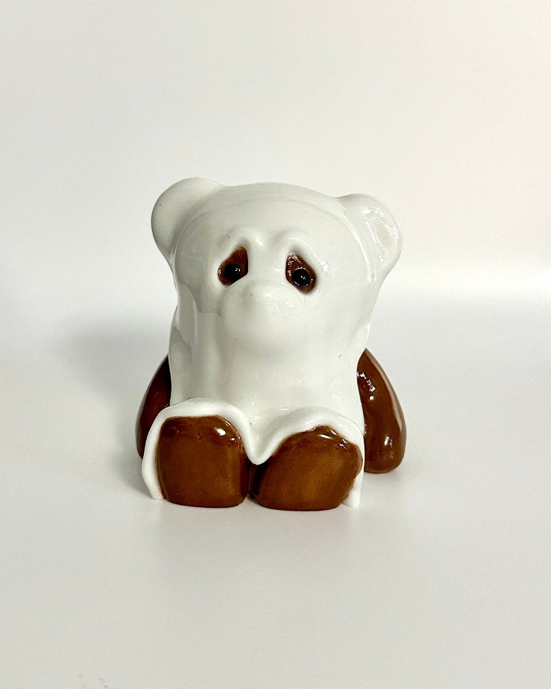 Small bear figurine with white face and brown body on a white background