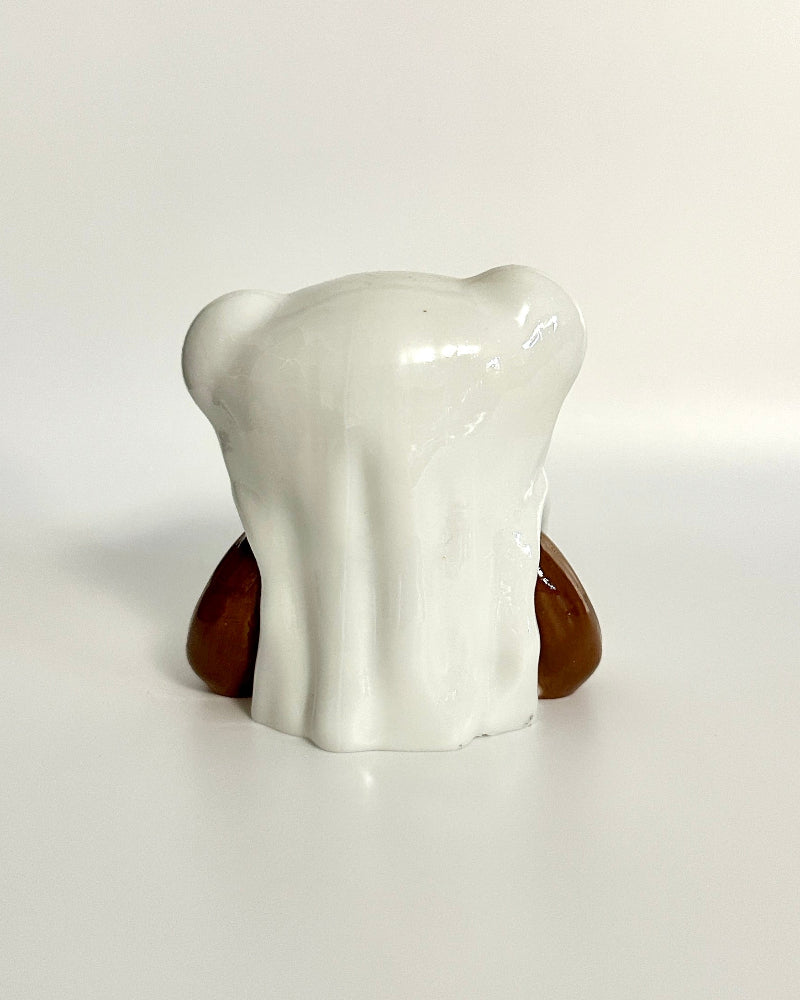 White ceramic tooth-shaped object on a wooden base against a white background