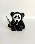 Panda figurine with a mask and knife on a white background