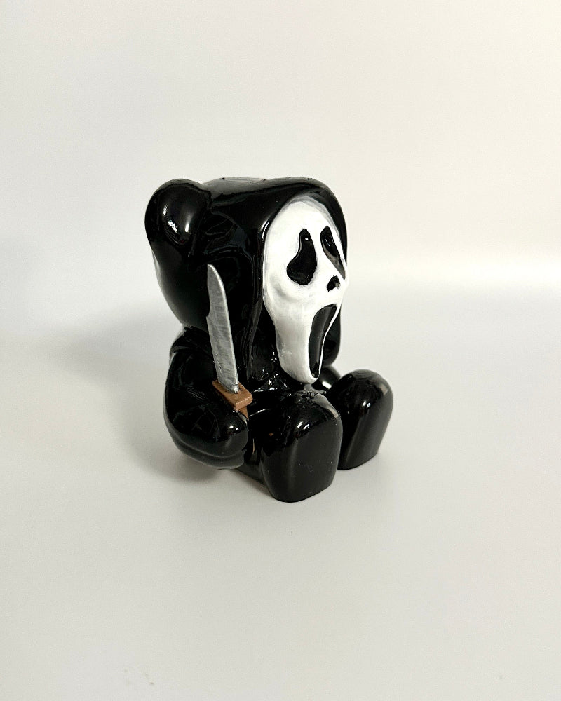 Black teddy bear with a ghost face design on a white background