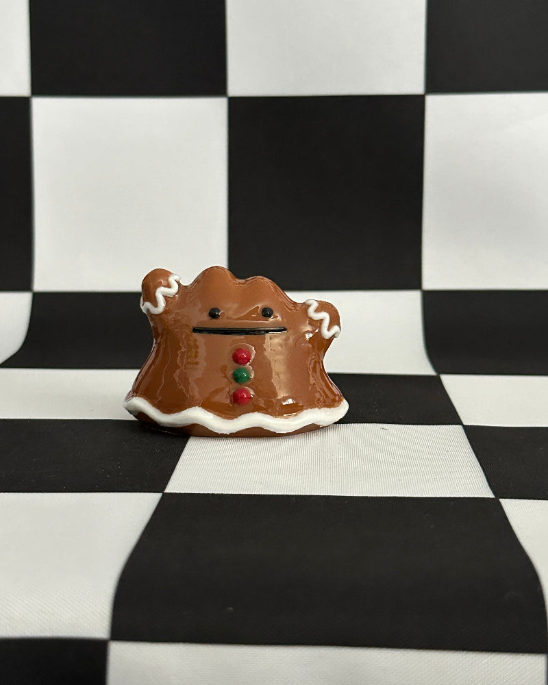 Small gingerbread man cookie on a black and white checkered background