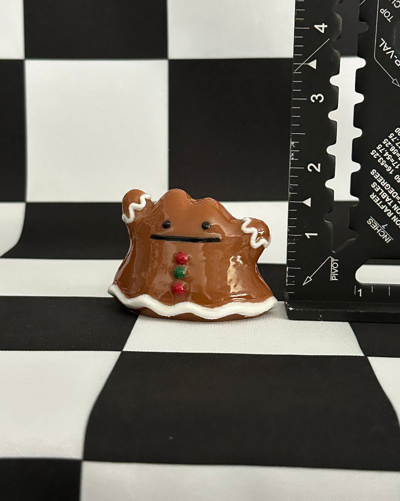 Small ceramic creature with a checkered background and ruler for scale