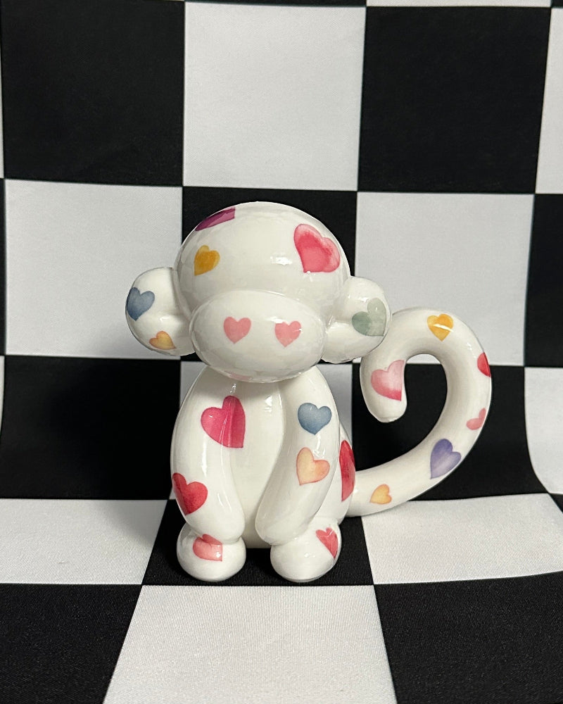  monkey figurine with colorful heart patterns on a black and white checkered background