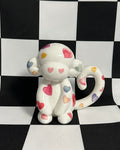  monkey figurine with colorful heart patterns on a black and white checkered background
