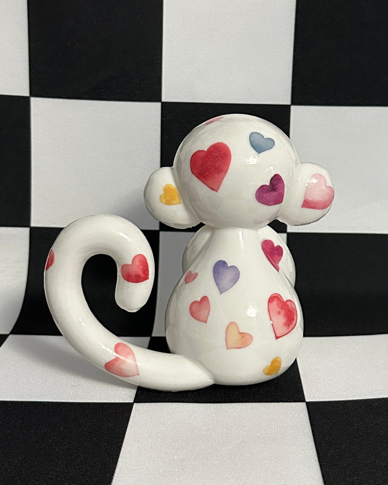 Small figurine with heart patterns on a black and white checkered background
