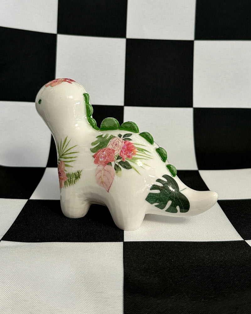 Decorative ceramic dinosaur with floral patterns on a black and white checkered background