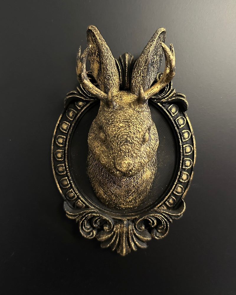 Decorative metal door knocker shaped like a deer head on a dark background