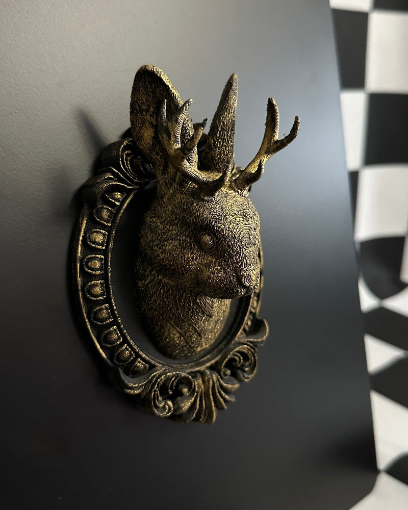 Decorative deer head wall art on a black wall with a checkered pattern.
