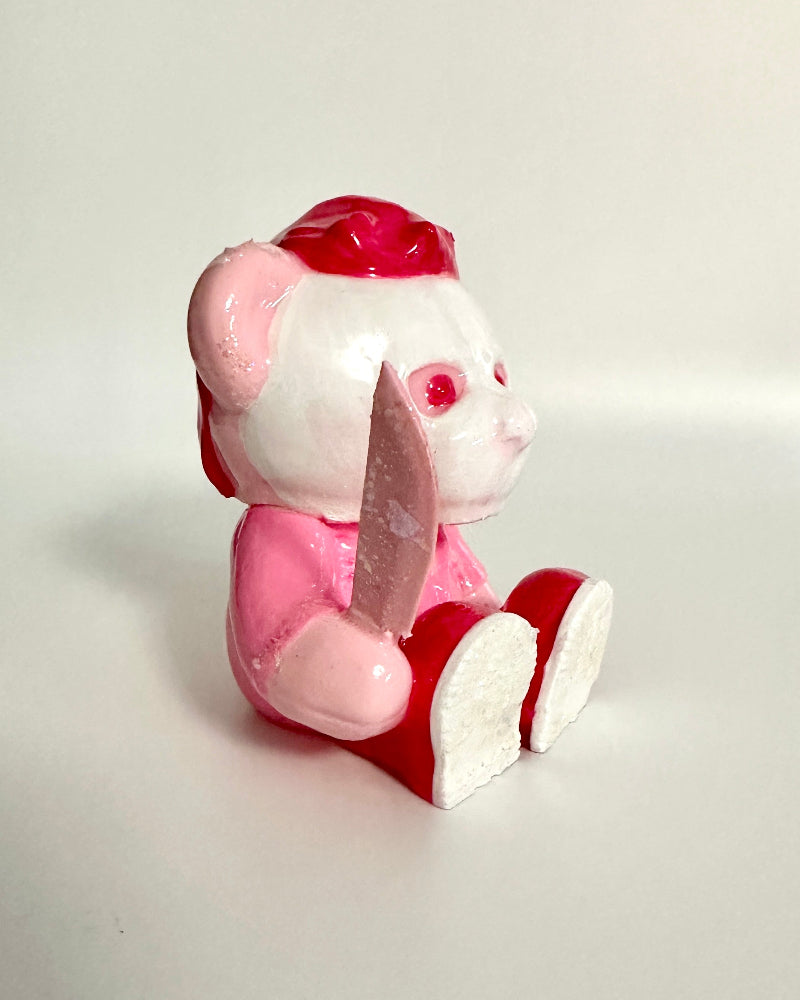 Small pink and red toy figure on a light gray background