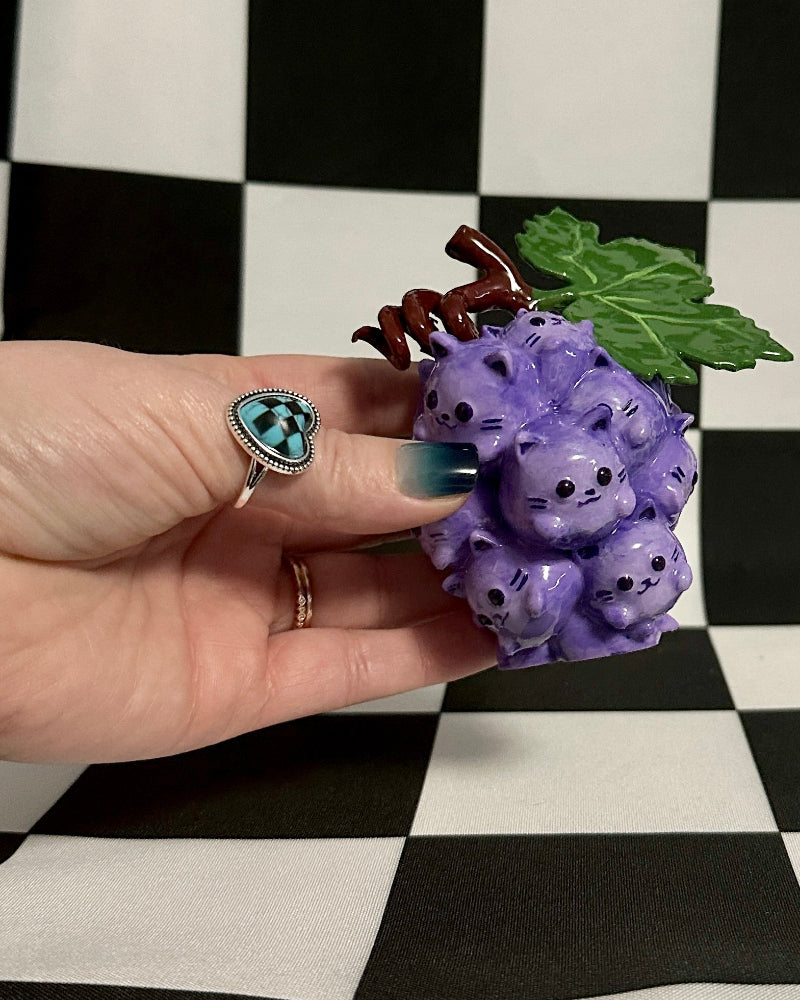 Hand holding a small decorative item resembling grapes on a checkered background