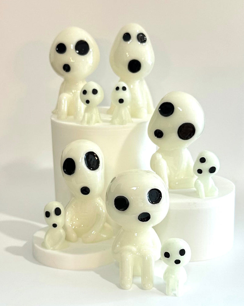 White ceramic figurines with black spots on a white surface