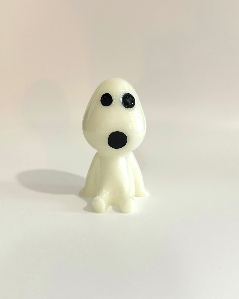 White figurine with black eyes and mouth on a light beige background