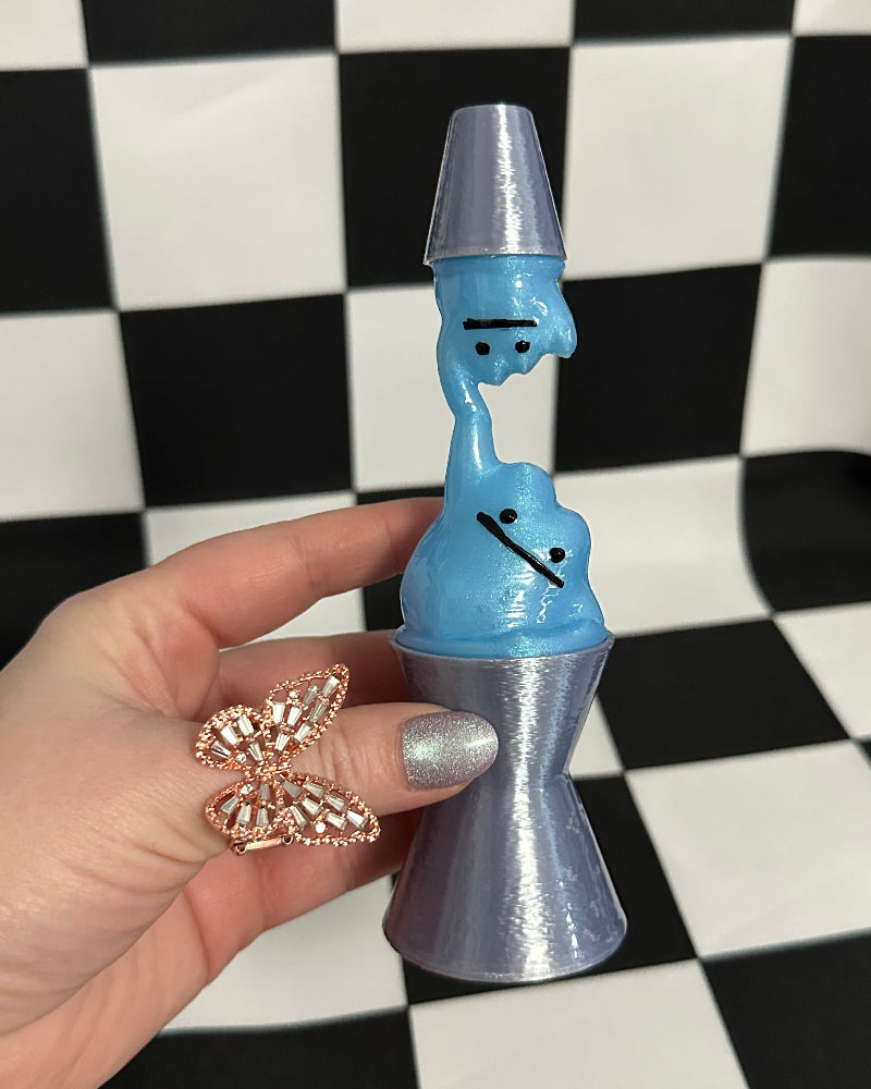 Hand holding a blue and silver novelty item against a checkered background