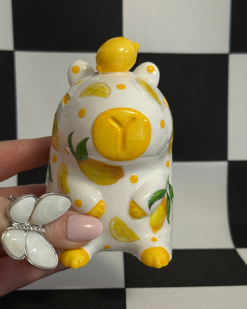 Decorative capybara with lemon design held against a black and white checkered background