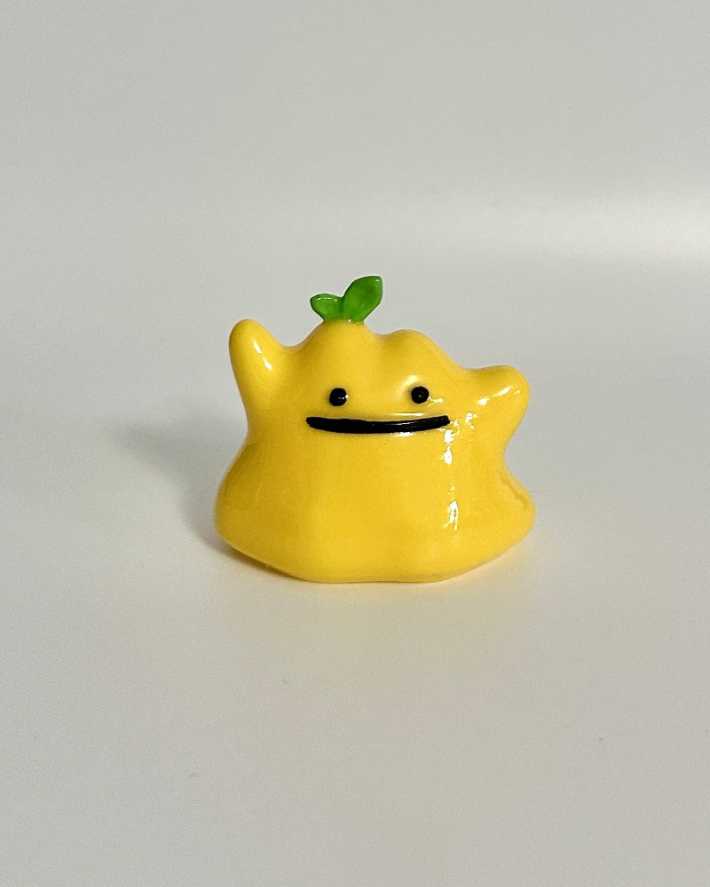 Small yellow figurine with a green leaf on a white background