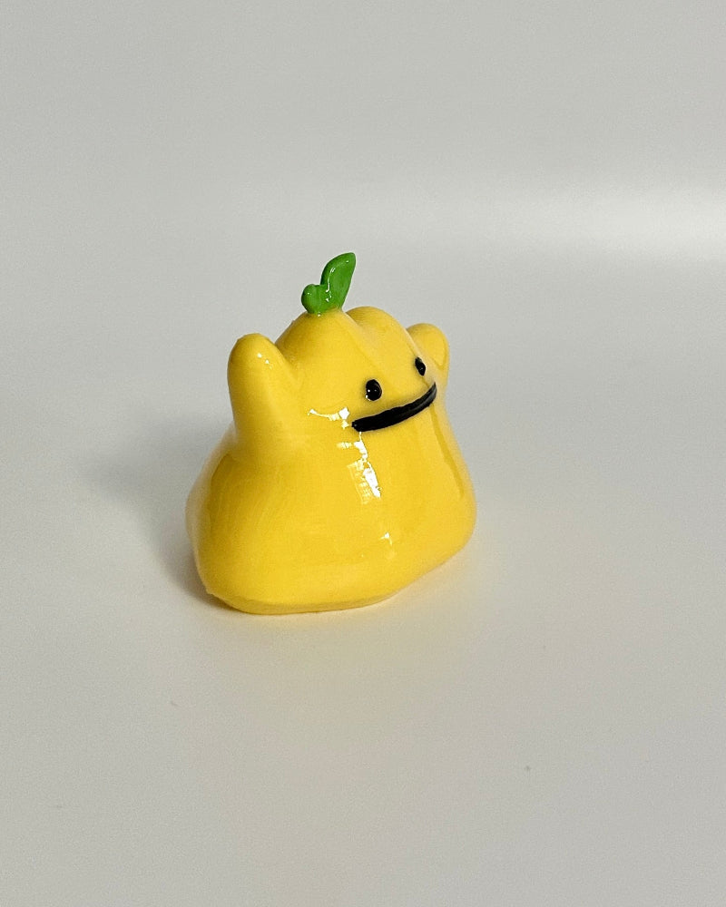 Yellow cartoon-like figurine with a green stem on a white background