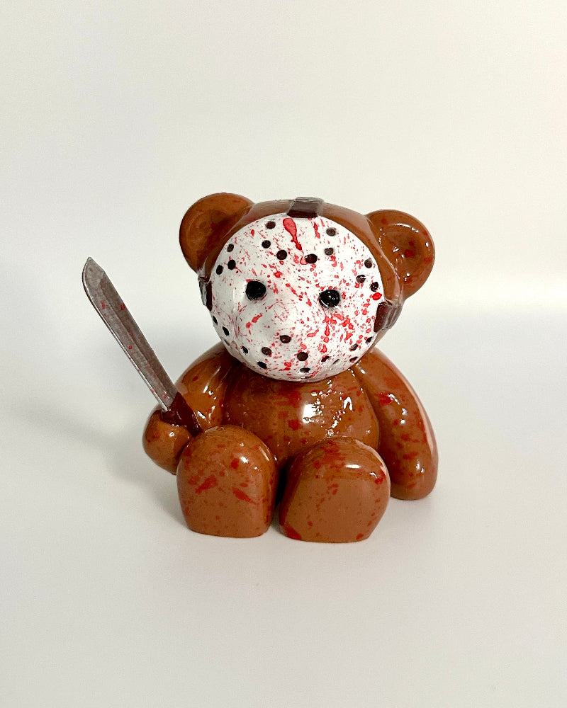 Teddy bear with a Jason Voorhees mask holding a knife on a white background