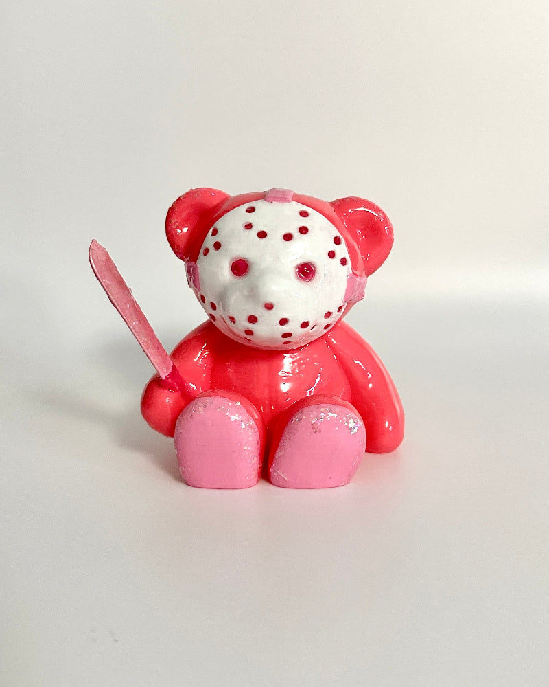 Pink teddy bear figurine with a white face and red polka dots on a white background