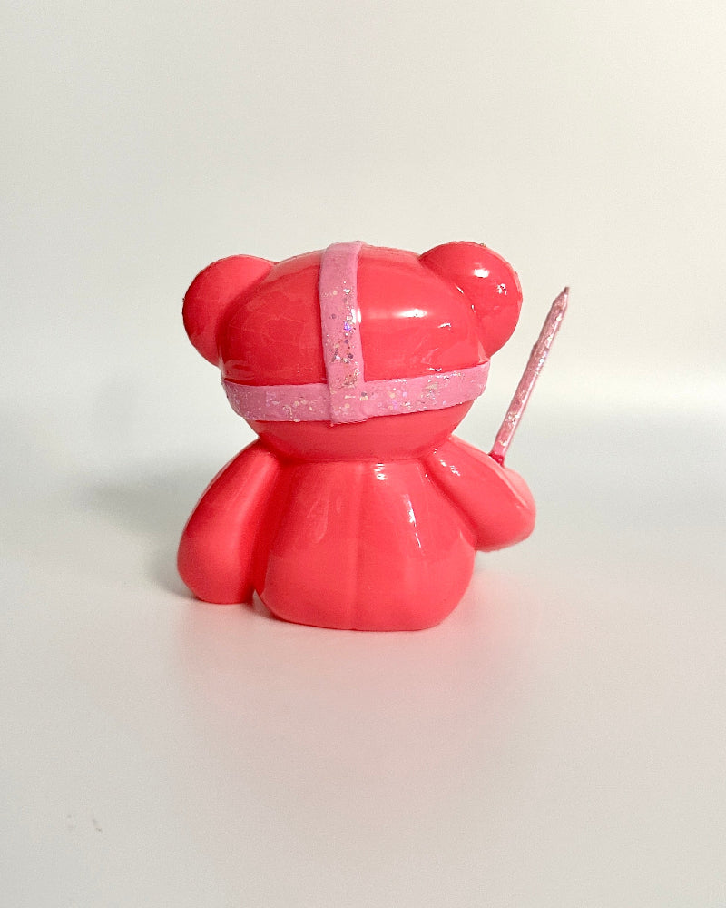 Red toy bear with a white ribbon on a white background