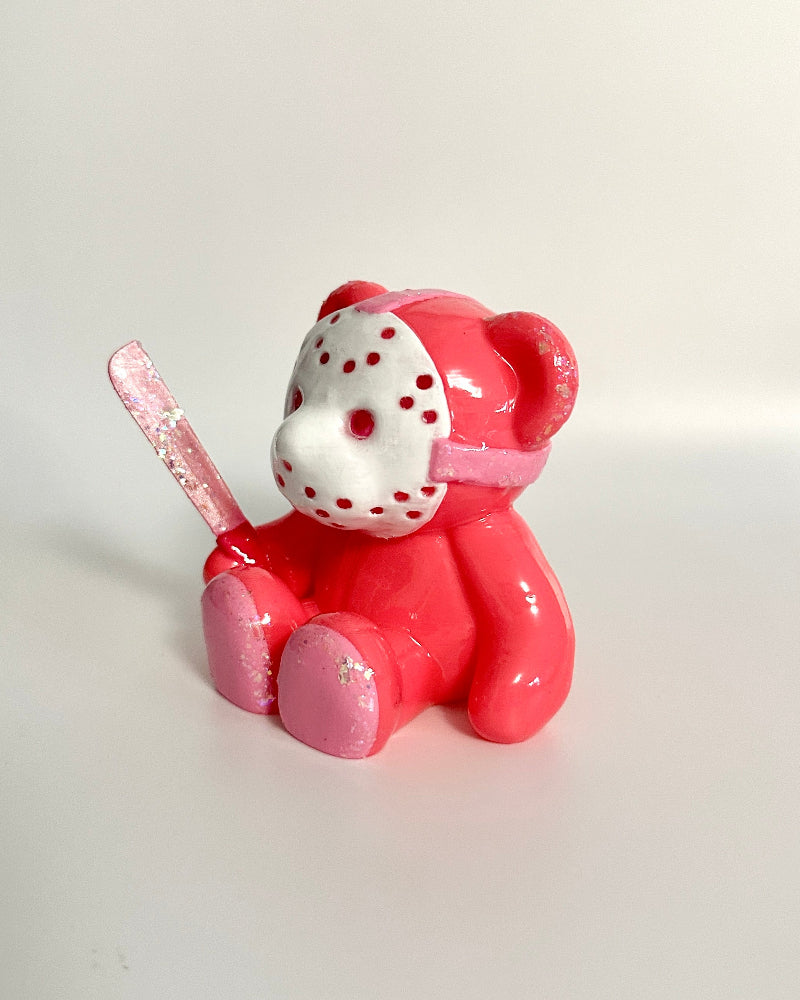 Pink teddy bear figurine with a face mask on a white background
