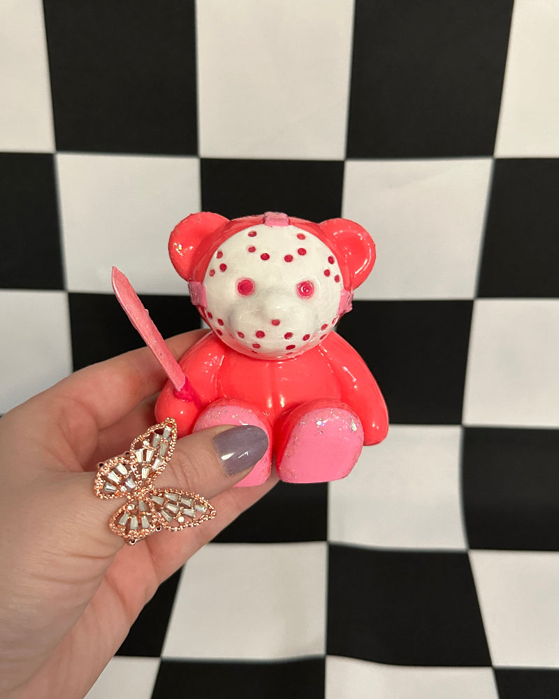 Pink teddy bear figurine with a black and white checkered background